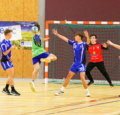 Joueurs de handball qui effectue une attaque au dessus du bloc adverse